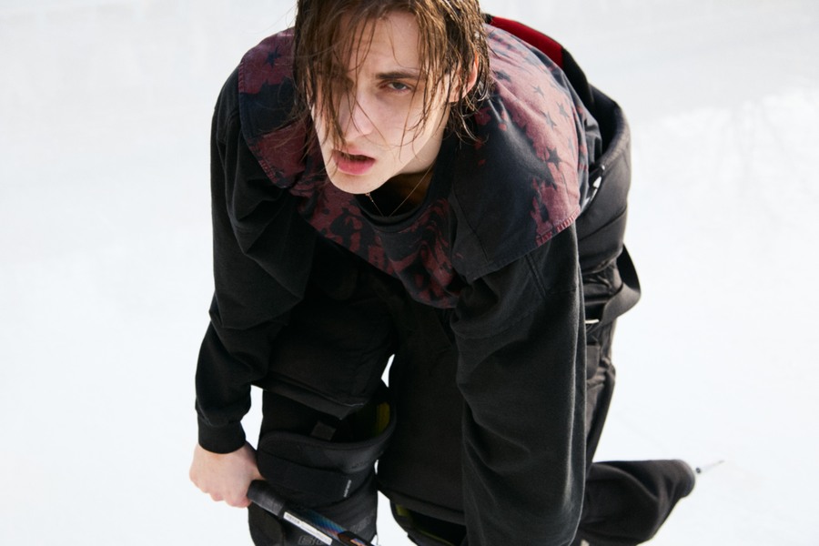 Photograph of Marks leaning towards the camera on the ice in black hockey equipment